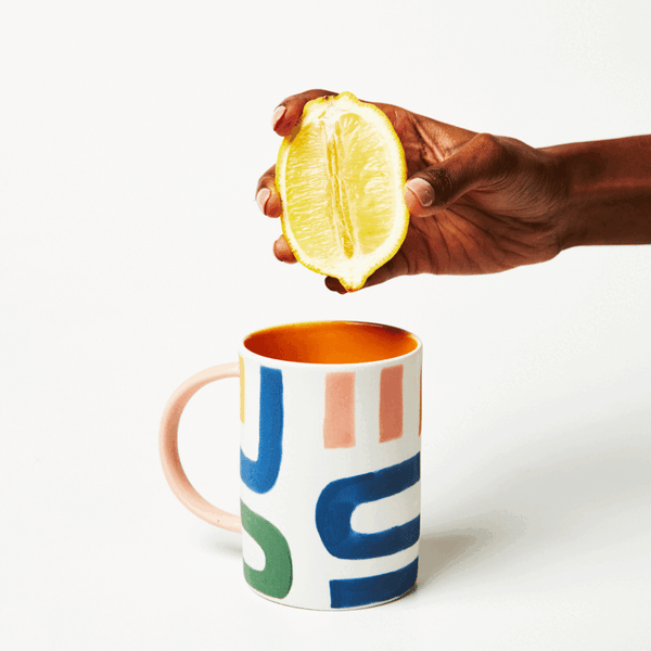Hand-painted ceramic mug with hand squeezing a lemon